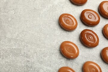 Many tasty caramel candies on grey table, flat lay. Space for text