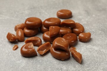 Many tasty caramel candies on grey table, closeup