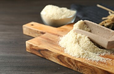 Pile of flour and scoop on dark wooden table, closeup