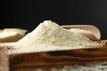 Pile of flour on wooden board against black background, closeup