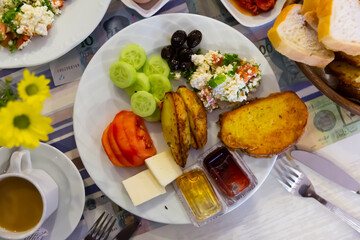 Breakfast at the hotel of tomatoes, cucumbers, potatoes, salad, cheese, olives and bread.
