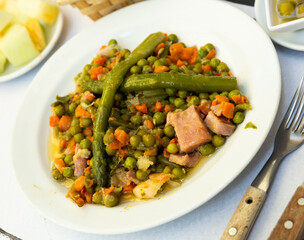 Dish of tasty stewed different vegetables with bacon at white plate