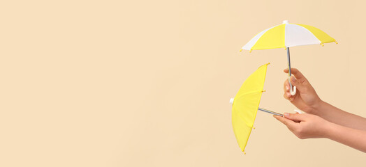Female hands with different mini umbrellas on beige background