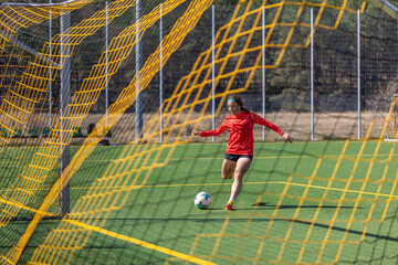Sporty girl scores a goal into the goal. Football concept. Girl on the football field.