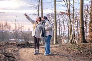 Two women in the forest. Woman pointing at the scenery. People in nature.