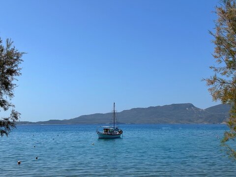 Sailboat anchored by the beach with a mountain backdrop, Adamantas, Milos, Greece