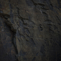 A textured stone background with chiaroscuro lighting, showcasing a brutal, monolithic rock formation. Cracks and fragments highlight its geological power, perfect for design templates or science