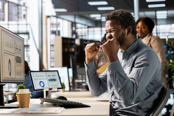 Happy corporate employee celebrating a major project milestone, thrilled with the successful...