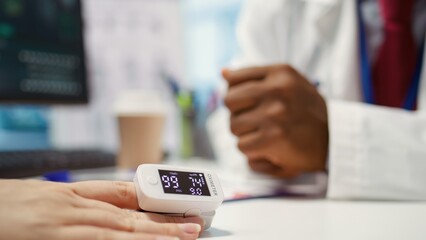 Physician using an oximeter on patient to measure oxygen levels and saturation, checking vital signs during examination at facility. Medic consulting a woman on health insurance. Close up. Camera B.