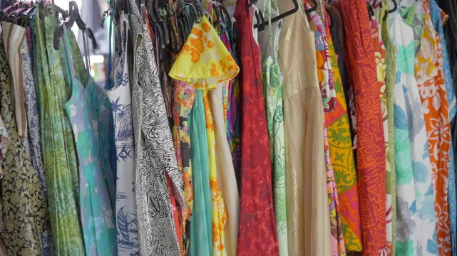 This panning video shows a many Polynesian style vintage dresses hanging together.