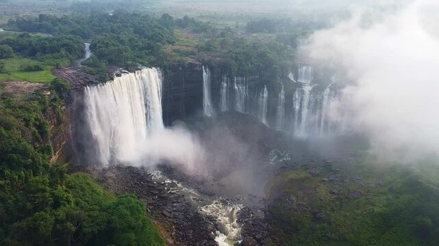 a breathtaking aerial view of waterfalls plunging into a misty pool, surrounded by lush, green trees Angola