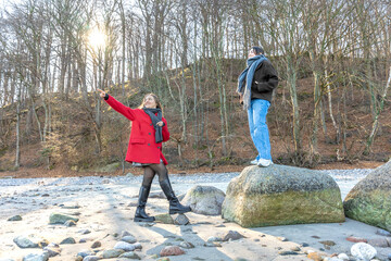 Happy friends walking by rock at beach. Two women on the rocks. Outdoors.