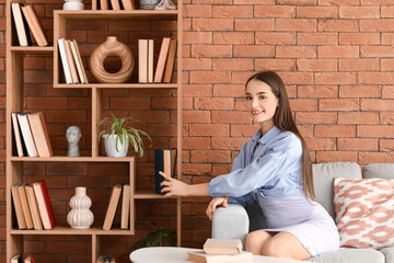 Young woman putting book on shelf in living room