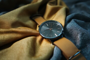 Elegant Watch on Draped Fabric: Stylish Timepiece Display with Soft Gold and Gray Textile Background