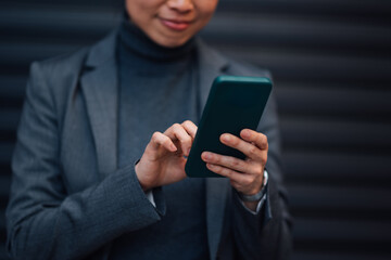 Businesswoman using smartphone in front of dark background
