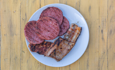 A plate of meat with a hamburger and bacon on it