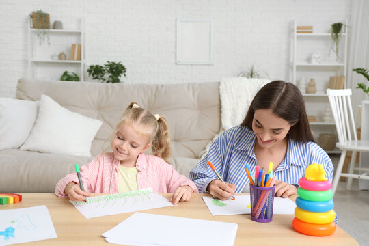 Nanny with cute little girl drawing on table at home - Powered by Adobe