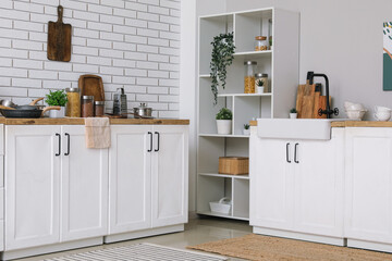 Kitchen counters and shelving unit near white brick wall in interior of kitchen