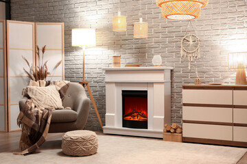 Interior of stylish cozy living room with fireplace, armchair and glowing lamps in evening