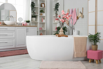 Interior of light bathroom with bathtub, sink and plants