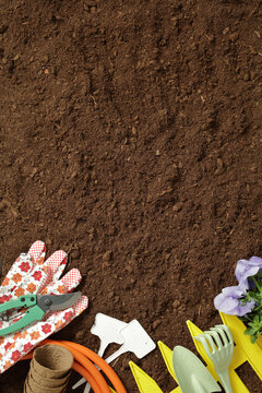 Gardening tools and soil background with floral accents