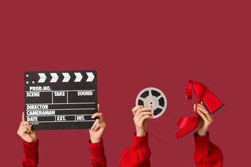 Female hands with film reel, movie clapper and heeled shoe on red background. Valentine's Day...