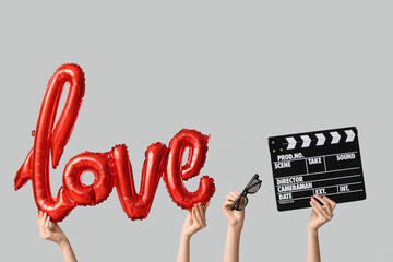 Female hands with 3D glasses, movie clapper and air balloon in shape of word LOVE on white...