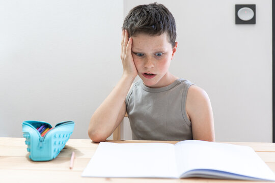 Young boy looking confused while studying with open book