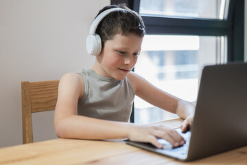 Child with headphones using laptop in bright room