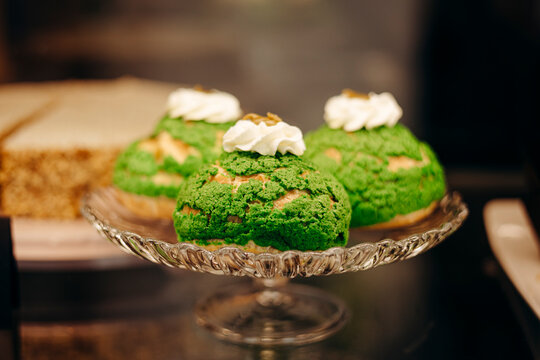 Matcha choux pastries with whipped topping on glass plate