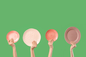 Young women holding different plates on green background