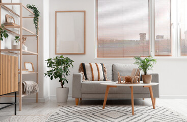 Fototapeta premium Cozy sofa, coffee table and blank poster in interior of living room
