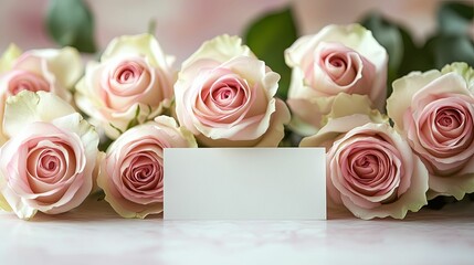 A bouquet of pastel pink and cream roses with a blank card.
