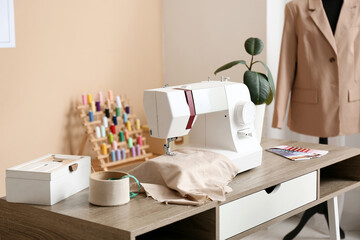 Sewing machine with cloth on tailor's table in atelier
