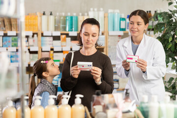 Woman with a child buys paracetamol, reads the instructions on the package and consults with a female pharmacist at the pharmacy. Buying tablets from the pharmacy
