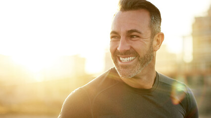 Happy, running and man in city in morning for exercise, marathon training and cardio workout in town. Sports, sunshine and person for wellness, rest and smile for performance, endurance and fitness