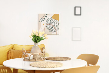 Vase with tulips on dining table in light room