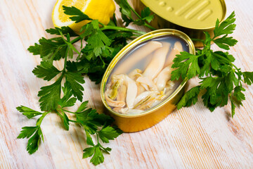 Gourmet canned natural marine mollusks Solen on wooden table with fresh parsley and lemon. Mediterranean seafoods..