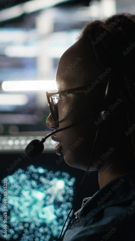 Poster vertical video data center employee uses audio headset and visual programming dashboard to troublesh
