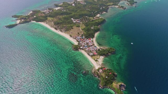 Aerial view of Malapascua Island in the Philippines, featuring vibrant turquoise waters, lush tropical vegetation, and colorful houses along the picturesque coastline
