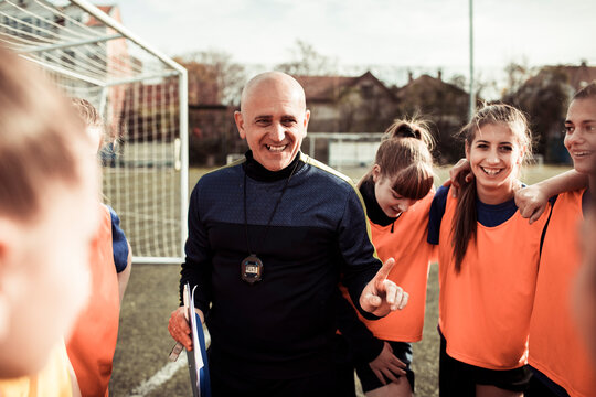 Soccer coach giving pep talk to girls team before game