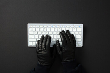 Hacker hands in black gloves typing on white keyboard. Cybercrime concept