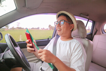 Naklejka premium asian men makes contactless payment for toll card with a smartphone while sitting in a car