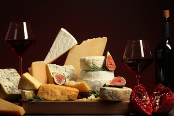 Different types of cheese, rosemary, figs, pomegranate and wine on table
