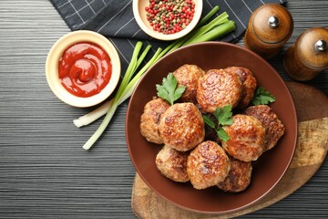 Delicious patties and spices on black textured table, flat lay. Space for text
