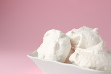 Delicious homemade meringue cookies in bowl on pink background, closeup