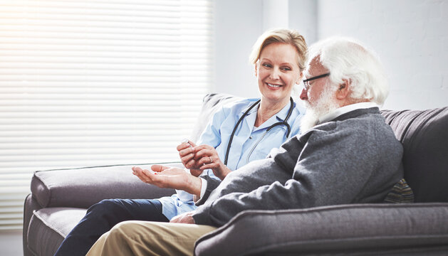 Senior man drinking medicine, taking pills and looking after health with help from a medical doctor, nurse or female carer. Sick, frail and retired male getting medication during checkup with gp