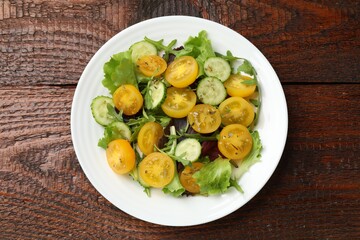 Fresh salad with yellow tomatoes on wooden table, top view