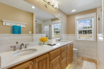 This is a spacious bathroom featuring two sinks, a toilet, and a large mirror