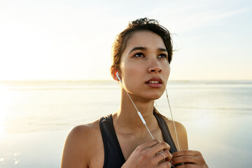 Thinking, woman and earphones of fitness at ocean for exercise, listening to music and training...